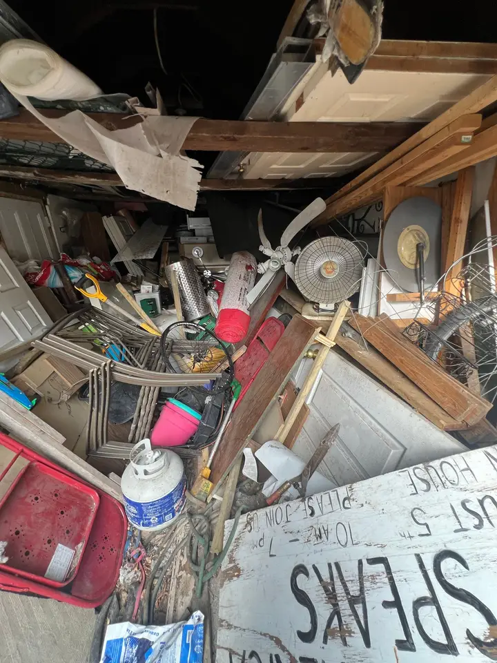 A garage packed to the rafters with doors, lumber, chairs and household junk